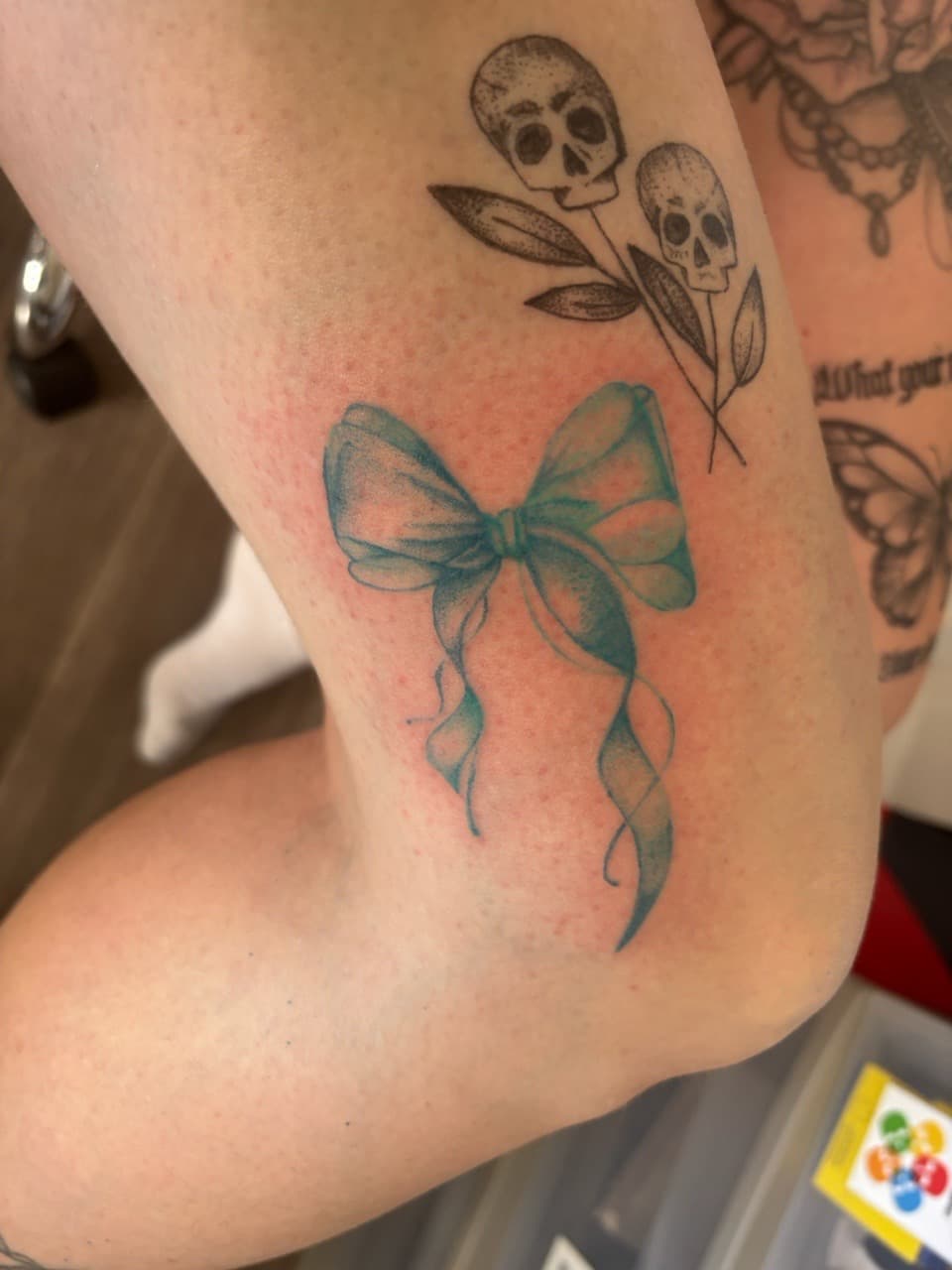 Watercolor + Fine Line bow tattoo on Upper Arm by Skull_Brothers_Ink on TattMe