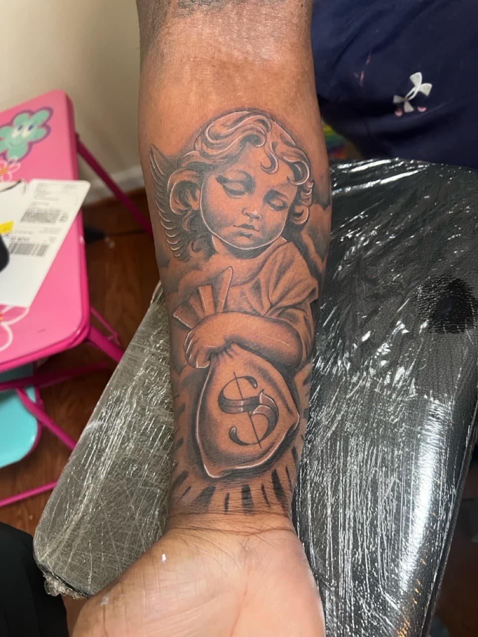 Black & Grey + Illustrative cherub tattoo on Forearm by Money_Ink_Tattoos on TattMe