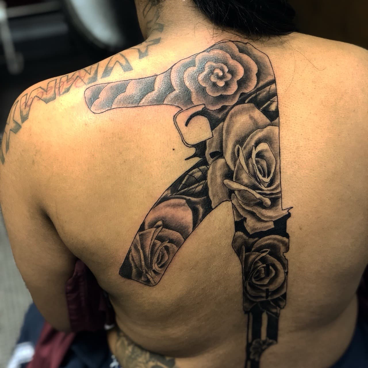 Black & Grey + Floral gun tattoo on Upper Back by Mafia_Ink on TattMe