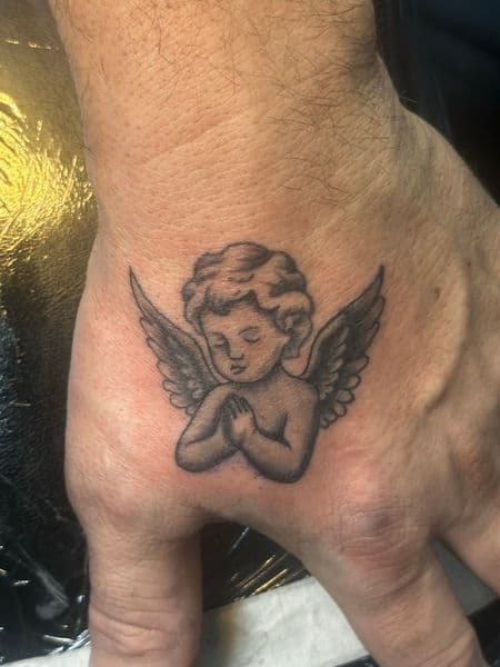 Black & Grey + Illustrative cherub tattoo on Hand by Jr on TattMe