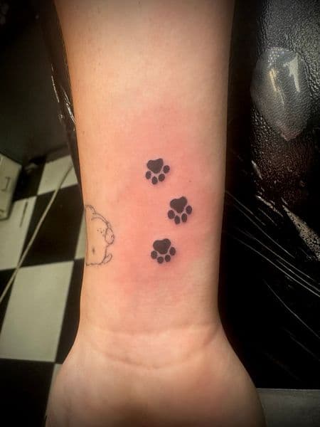 Minimalist + Black-work paw prints tattoo on Wrist by Jr on TattMe