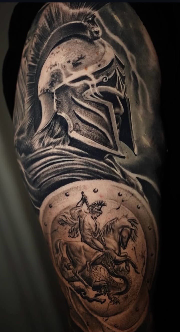 Black & Grey + Realism spartan helmet tattoo on Upper Arm by Tattoosbyjm on TattMe